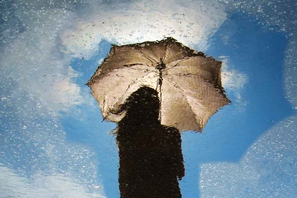 New Normal for Cancer Survivors - woman with umbrella in clearing sky