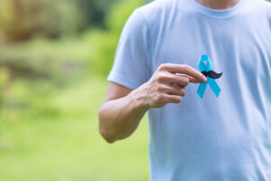 Prostate Cancer Awareness: Man holding blue cancer ribbon with mustache